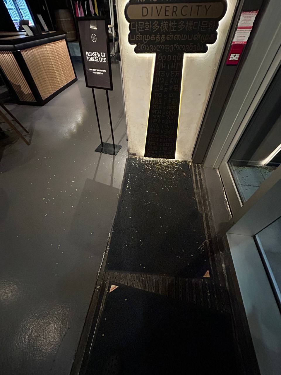 Restaurant entrance before cleaning — debris on mats and floor